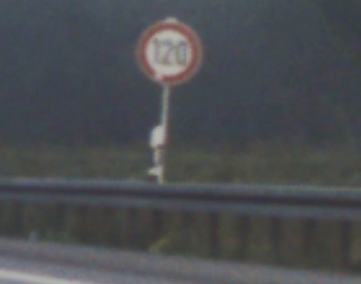 A 120 km/h speed-limit sign in thick fog.